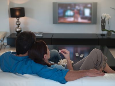 Couple watching television together and eating popcorn