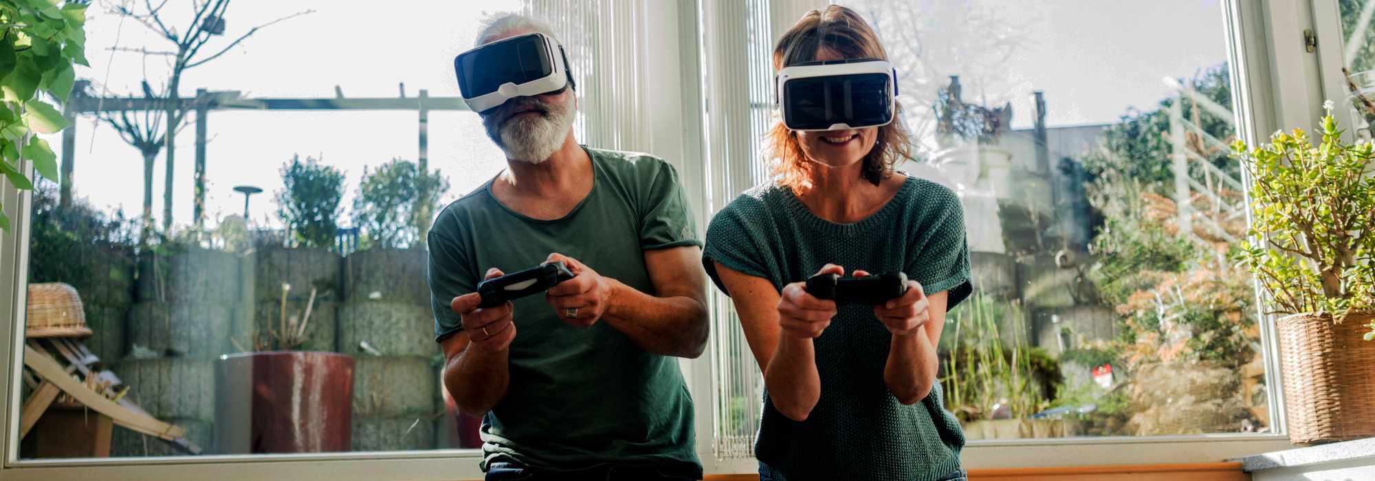 Man and woman wearing VR headsets and holding controllers playing a game.