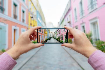 Personal perspective of a man photographing colorful street Rue Cremieux with smartphone, Paris, France