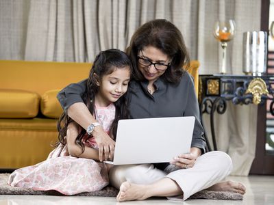 Two people using a laptop on the floor