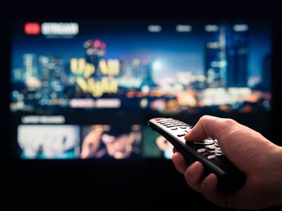 Person pointing a remote control at a TV.