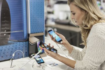 A woman comparing two smartphones in a store