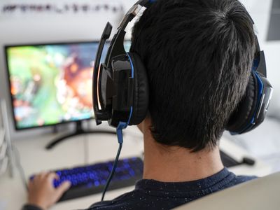 A view of the back of someone's head while they play a game on a monitor just in front of them