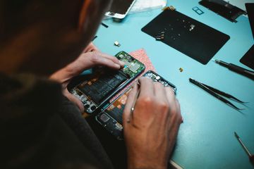 A technician repairing a phone on a blue workbench