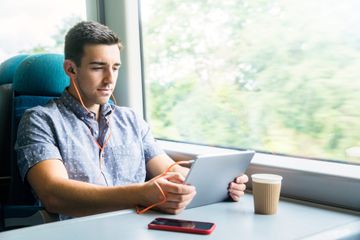 Man with tablet and headphones on train