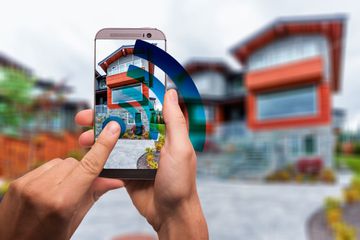 A person using a smartphone to snap a photo of a house.